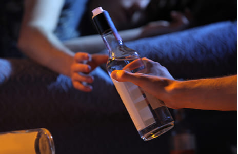 Пьяному протягивают бутылку с алкоголем