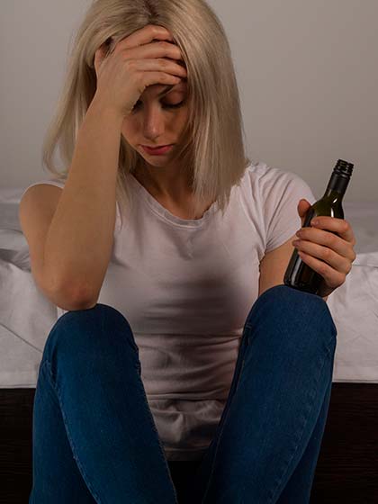 девушка сидит на полу с бутылкой алкоголя